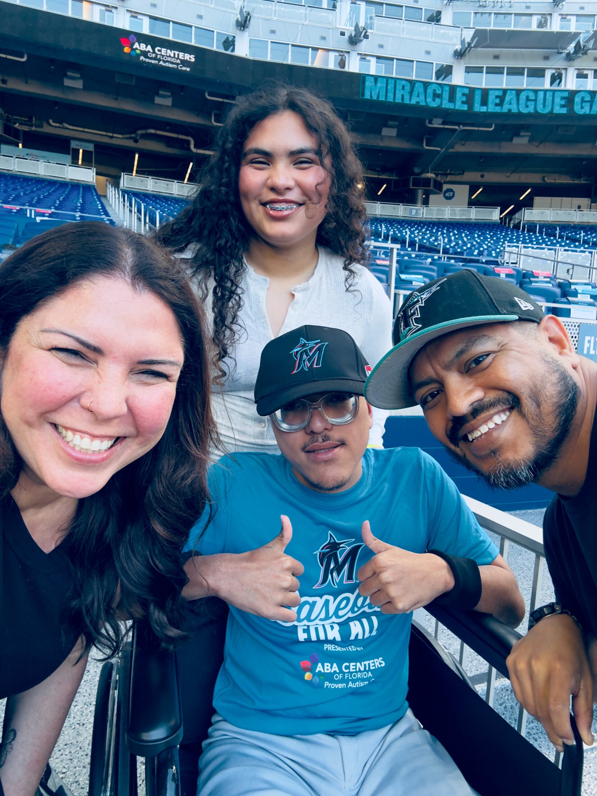 Jaenette R. smiling with her family at a baseball stadium event