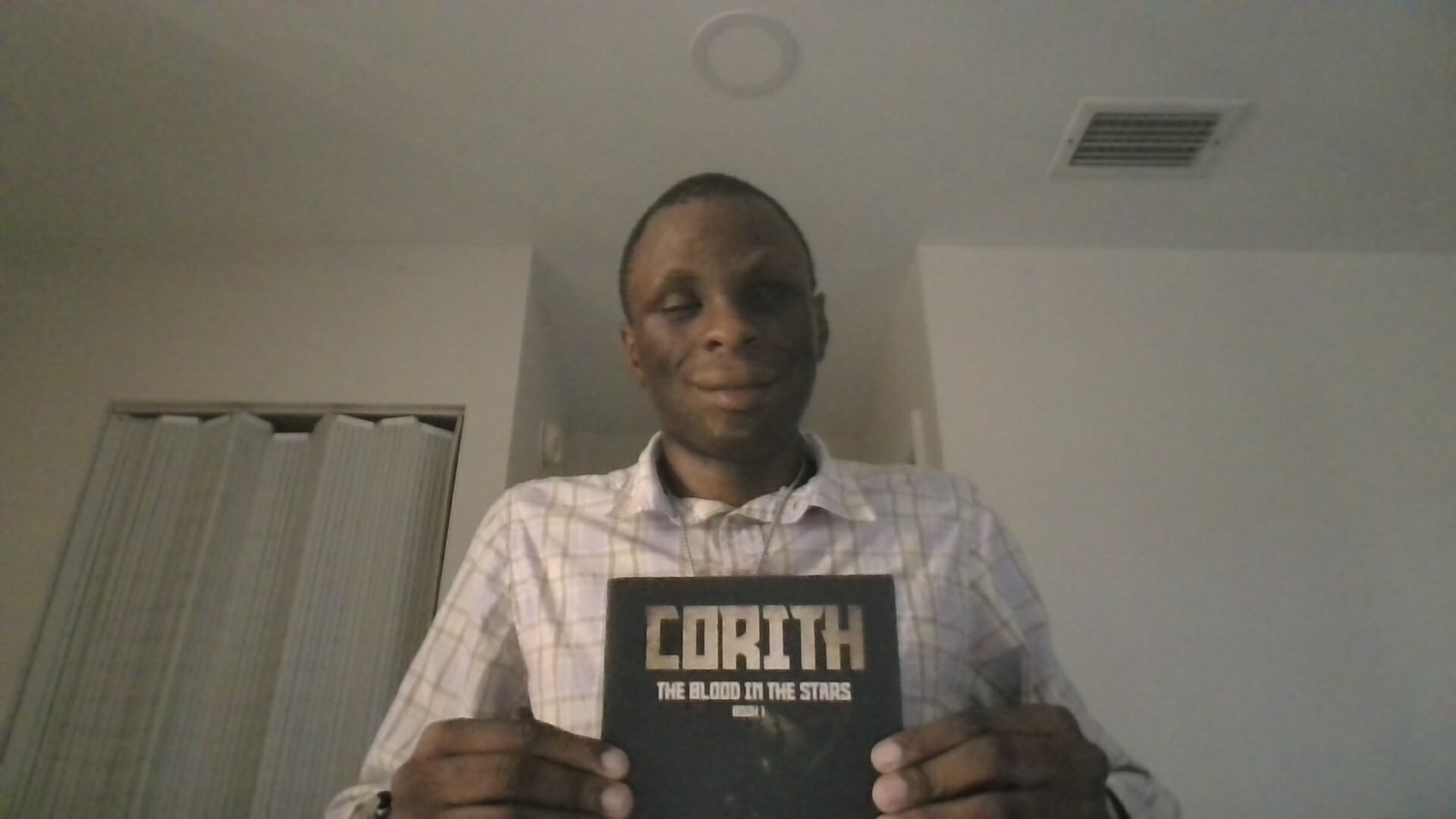Joshua V. smiling and holding a copy of his published book, Corith: The Blood in the Stars, Book 1.